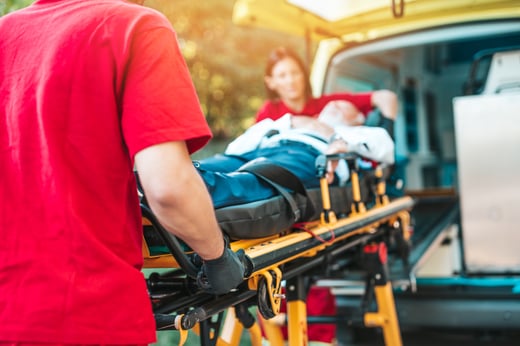 Ambulansepersonell som triller pasient inn i bil